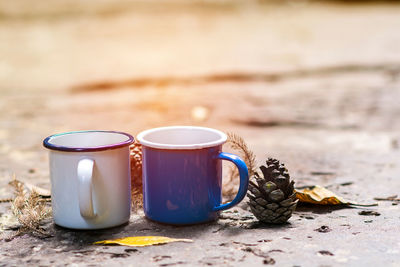 Close-up of coffee cups and pine cone