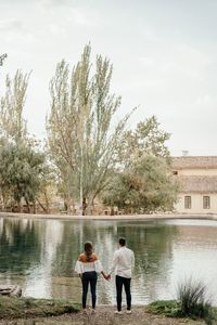Rear view of people standing by lake against sky