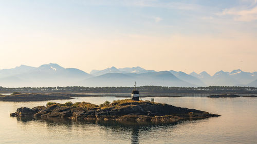 Scenic view of sea by mountain against sky