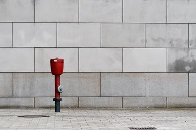 Fire hydrant on footpath against wall