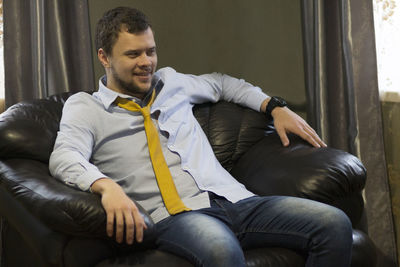 Young man looking at while sitting on sofa