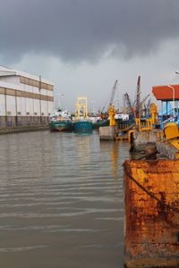 Boats moored at harbor against sky in city