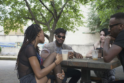 A group of friends having a conversation at a picnic table.