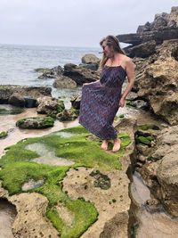 Woman standing on rock by sea