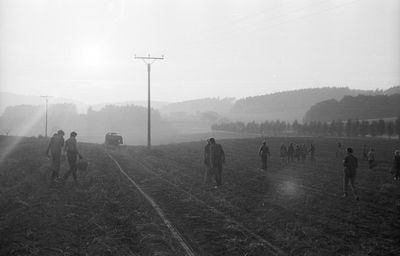 People walking on field against sky