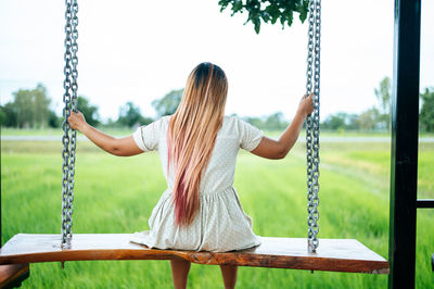 Rear view of woman sitting on swing at playground