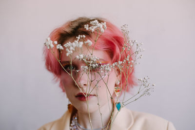 Young fashion stylish woman posing with gypsophila branch, bright make up and colored hair