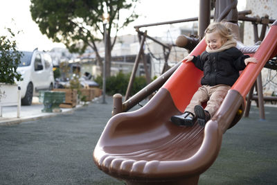 Baby girl sliding,warm clothing child,kid,toddler, infant of 1-2 year having fun in playground 