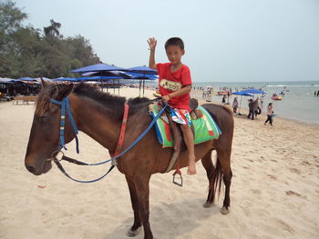 Full length of boy riding horse at beach