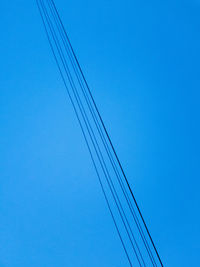 Low angle view of cables against clear blue sky