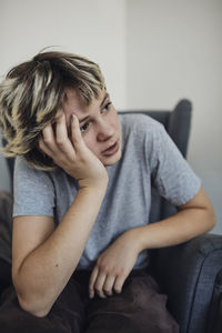 Female student with head in hand sitting on chair inside school office