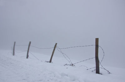 Damaged barbed wire fence on snow covered field