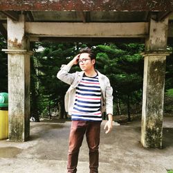 Young man with hand in hair looking away while standing outdoors