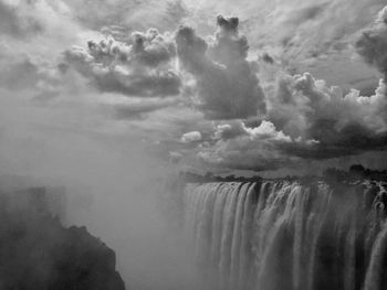 Scenic view of waterfall against sky during foggy weather