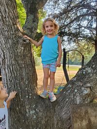 Full length of happy girl on tree trunk