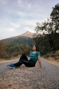 Woman with arms raised on mountain against sky