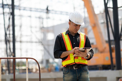 Man using mobile phone while standing at construction site