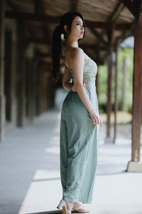 Portrait of young woman standing on footpath