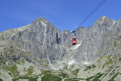 Low angle view of overhead cable car against mountains