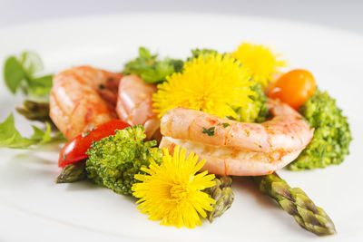 Prawns, asparagus and broccoli with edible dandelion flowers. selective focus.