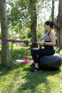 Woman sitting on tree trunk in field