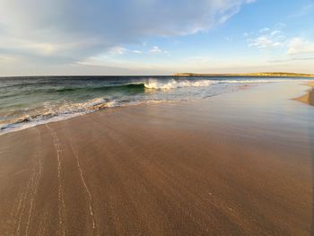 Scenic view of beach waves receding against sky 