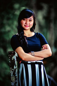 Portrait of young woman standing against trees