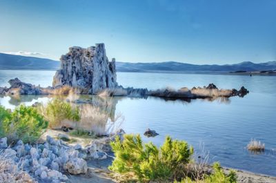 Scenic view of sea and rocks against blue sky