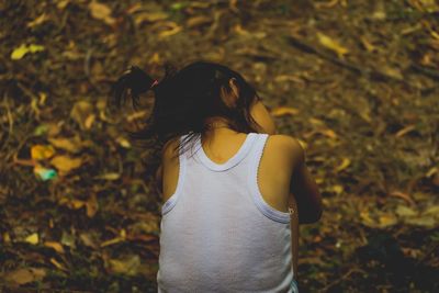 Rear view of girl sitting on field