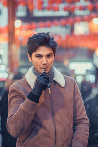 Portrait of man standing against illuminated city at night