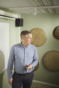 Side view of young man standing against wall