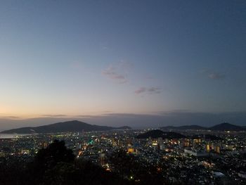 Illuminated cityscape against sky during sunset