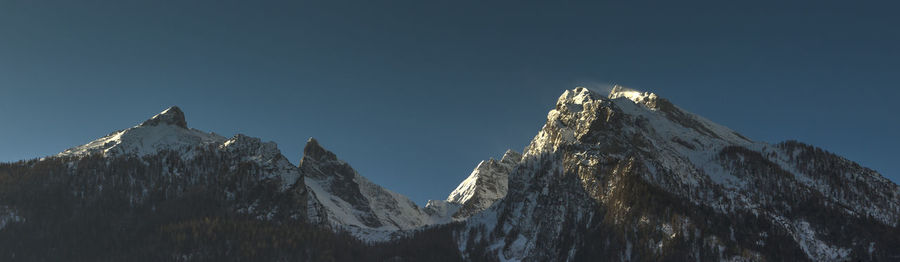 Panoramic view of rocky mountains against clear blue sky