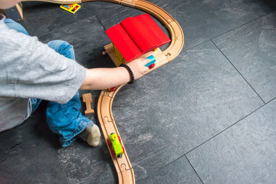 Cropped image of boy playing with train set on floor at home