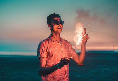 Young man using mobile phone at beach against sky