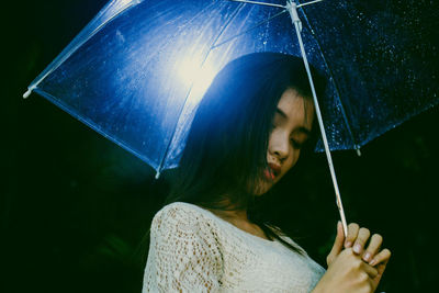 Young woman holding wet umbrella