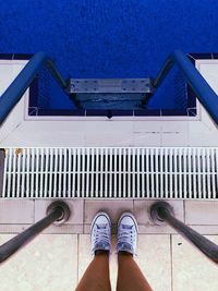 Low section of woman standing by swimming pool