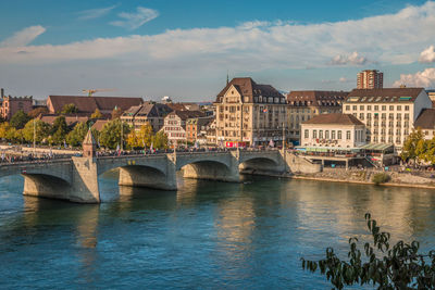 Bridge over river by buildings against sky in city