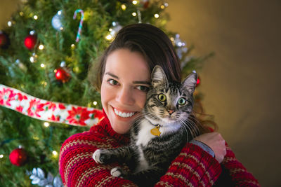 Portrait of smiling young woman holding christmas tree