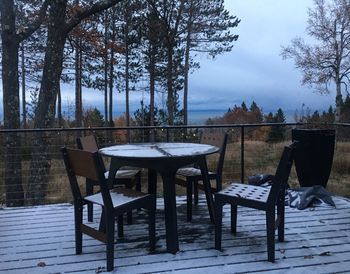 Empty chairs and tables against clear sky during winter