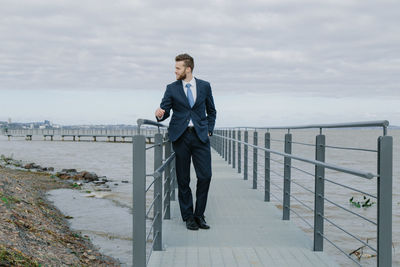 Full length of man standing on railing against sea