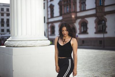 Young woman standing against wall in city