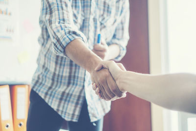 Cropped image of person shaking hands with male colleague in office