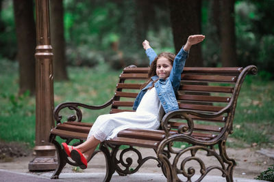 Portrait of girl sitting on bench in park