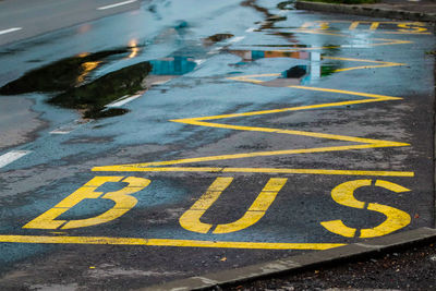 Yellow bus station marking on the road after a rainy day