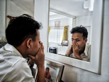 Depressed man looking in mirror