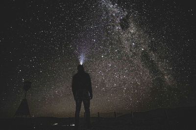 Rear view of man standing against sky at night