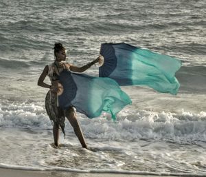 Full length of man holding umbrella on beach