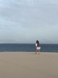 Full length of woman standing on beach against sky