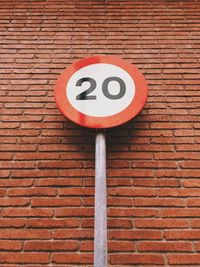 Low angle view of road sign on brick wall